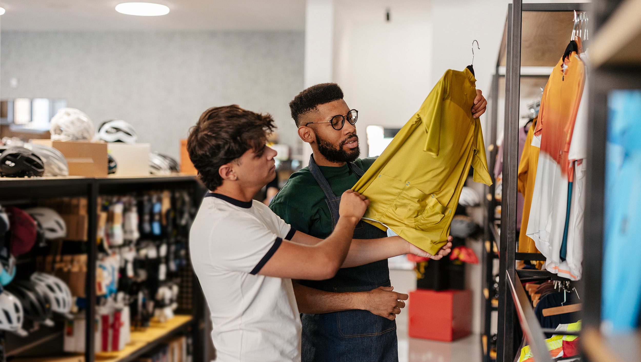 Winkelmedewerker adviseert een klant bij de aanschaf van een fietsshirt